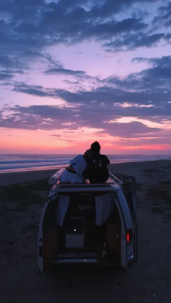 Mexican couple watching the sunset from the roof of a van for rent in Mexico